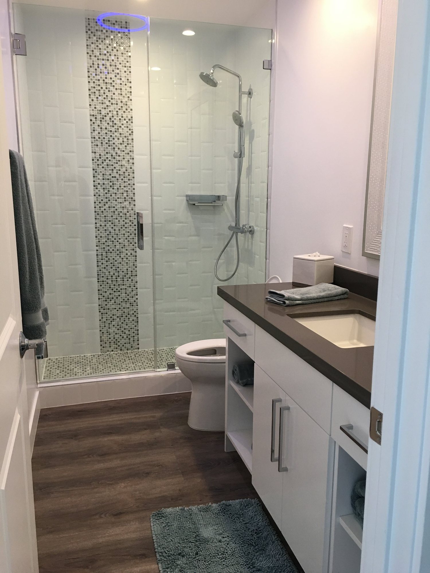 Bathroom with a glass walk-in shower, white tile with a mosaic accent strip, and a white vanity with dark counter